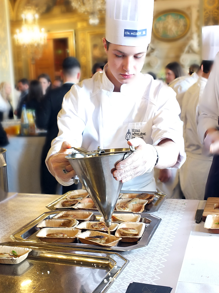 Image of a young trainee chef preparing food samples in the Paris city hall.