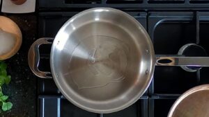 Top down image of sunflower oil in a rather lovely looking copper tri-ply saute pan.