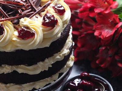 Layers of rich chocolate cake drizzled with cherry brandy sandwiched together with sweetened whipped cream and black cherry conserve. The cake is finished with more cream and some dark chocolate curls.