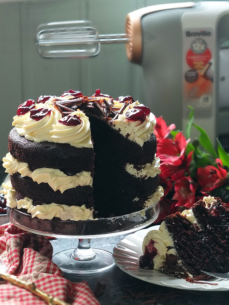 Layers of rich chocolate cake drizzled with cherry brandy sandwiched together with sweetened whipped cream and black cherry conserve. The cake is finished with more cream and some dark chocolate curls. #chocolate #chocolatecake #blackforestcake #baking