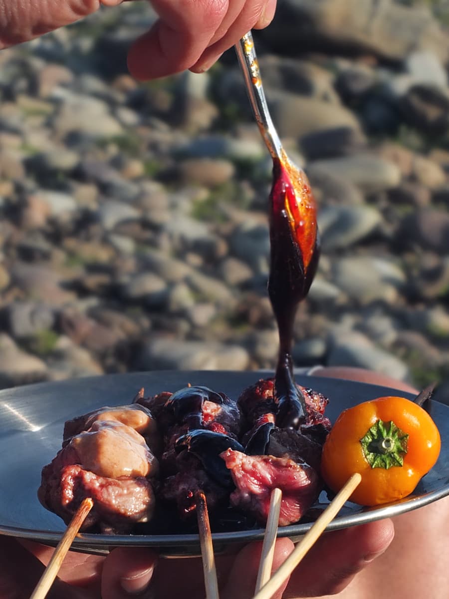 Image of BBQ lamb skewers with hoisin dipping sauce dripping off a spoon.