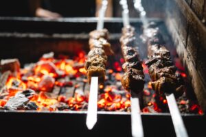 Image of a recipe for lamb skewers cooking on a barbecue.