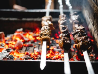 Image of a recipe for lamb skewers cooking on a barbecue.