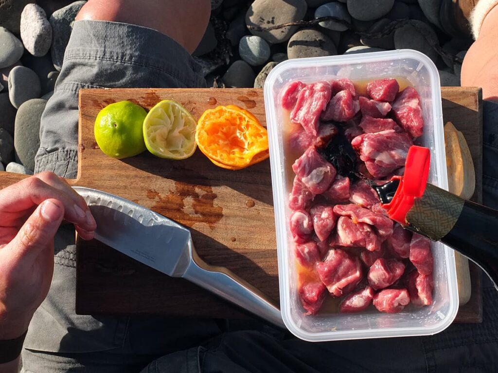 Image of man pouring soy sauce over lamb to marinade.