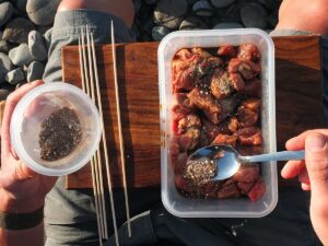 Image of man sprinkling spices over lamb.