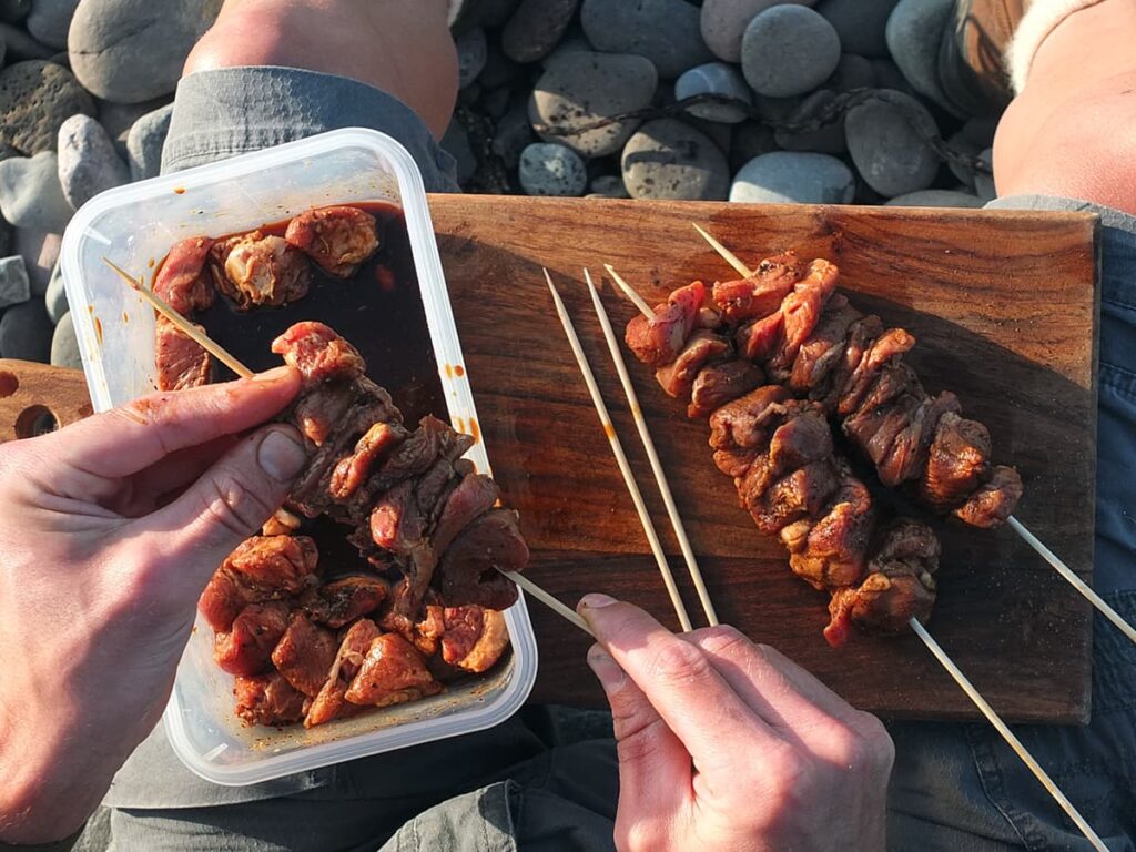 Image of man threading marinaded lamb onto bamboo skewers for the barbecue.