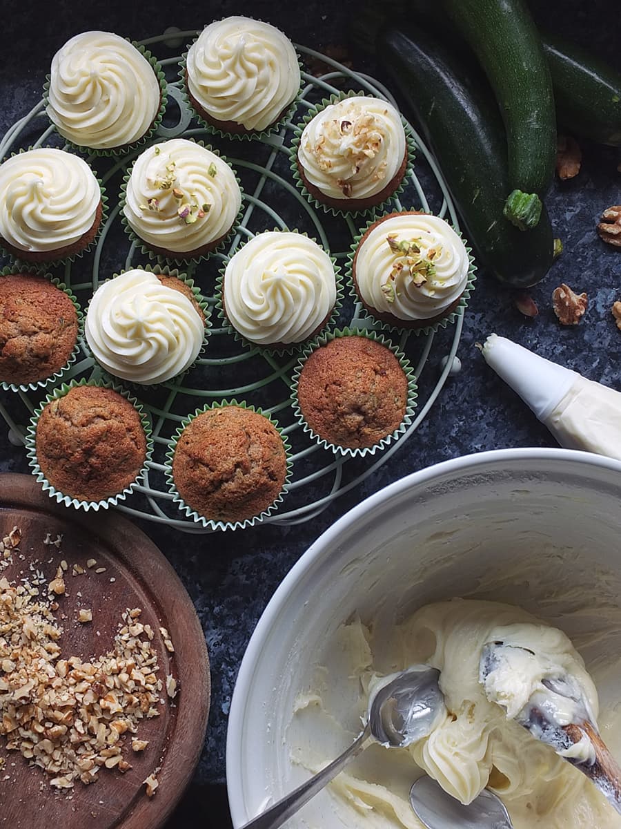 Top down image of cupcakes being frosted with cream cheese frosting.