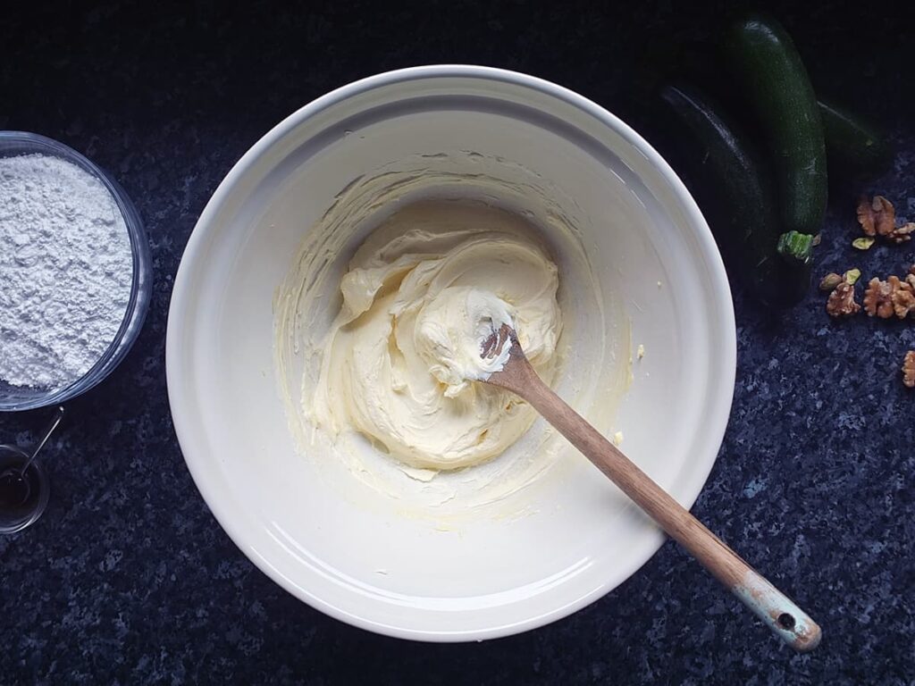 Photo of butter and cream cheese beaten together until smooth in a bowl.
