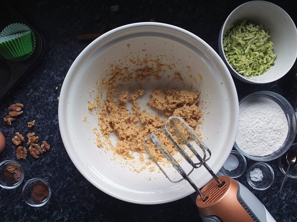 Image of butter and sugars creamed together in bowl with mixer at the side.