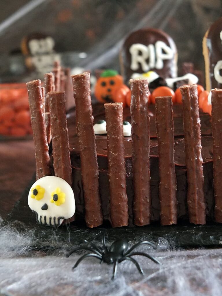 Close up photo of Quality Street Matchmakers spooky crooked graveyard fence on cake.