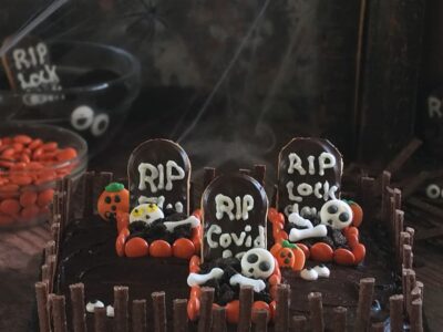 Image of a chocolate Halloween graveyard cake with three spooky graves surrounded by a chocolate matchmakers crooked fence.