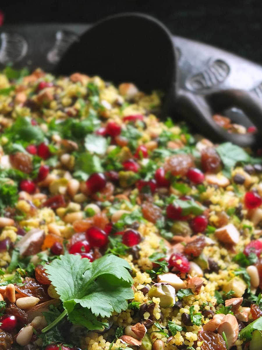 Close up image of jewelled couscous with a fresh coriander leaf focused in the bottom left hand corner.