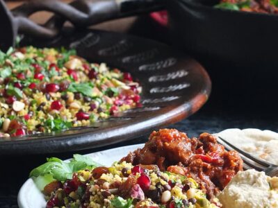 Image of jewelled couscous recipe on a serving plate with Moroccan-style slow cooked lamb, hummus, flatbread and plain yoghurt.