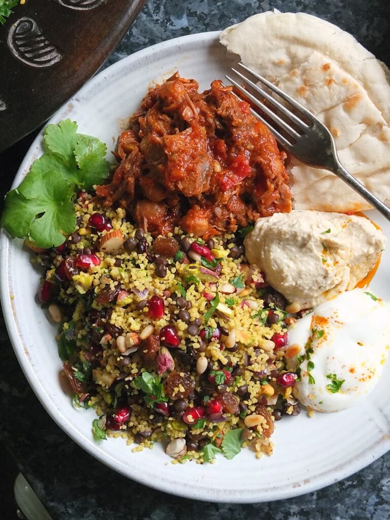 Image of jewelled couscous on a plate with slow cooked lamb and side dishes. I ate this plate of food after I photographed it and it was lovely.