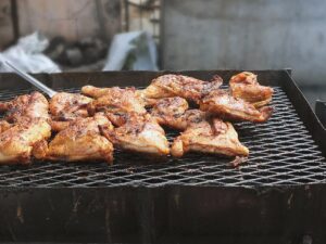 Image of meat barbecuing on black oil drums in the Caribbean.