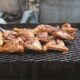 Image of meat barbecuing on black oil drums in the Caribbean.