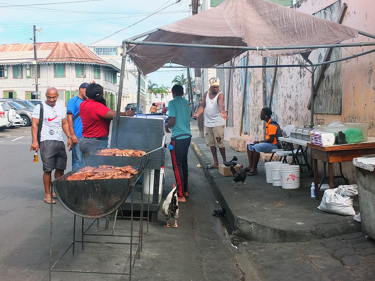 Image of Black Table Grill St. Kitts showing men standing around barbecue oil drums waiting for the meat to cook.