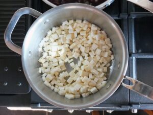 Image of celeriac cut into small pieces in a pan.