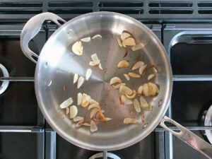 Top down image of shallots and garlic cooking in a saute pan.