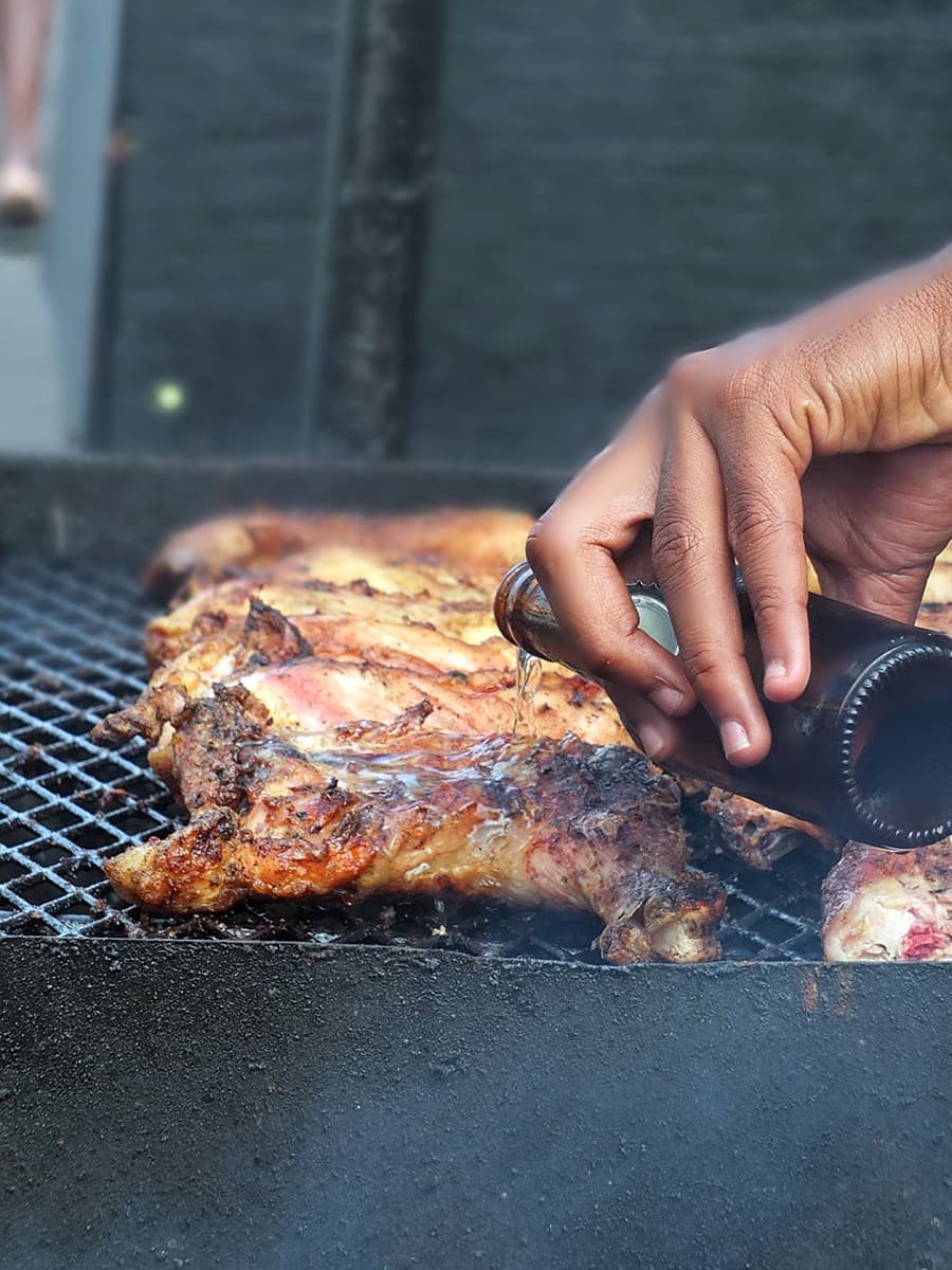 Image of beer being poured over bbq meat.