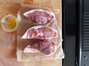 Image of lamb rump steaks drizzled with olive oil and seasoned with salt and pepper.