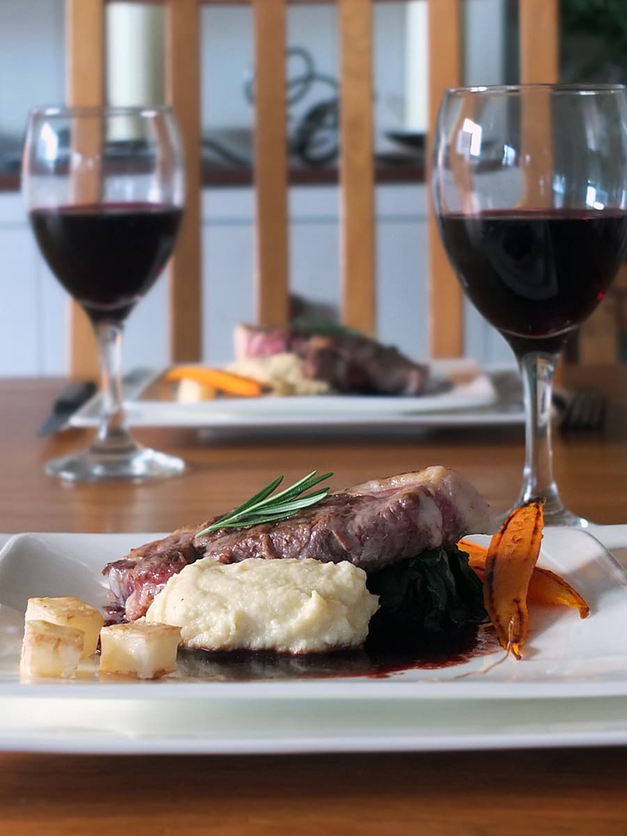 Image of a square white dinner plate with lamb leg steaks, celeriac puree and red wine jus for a romantic meal in.