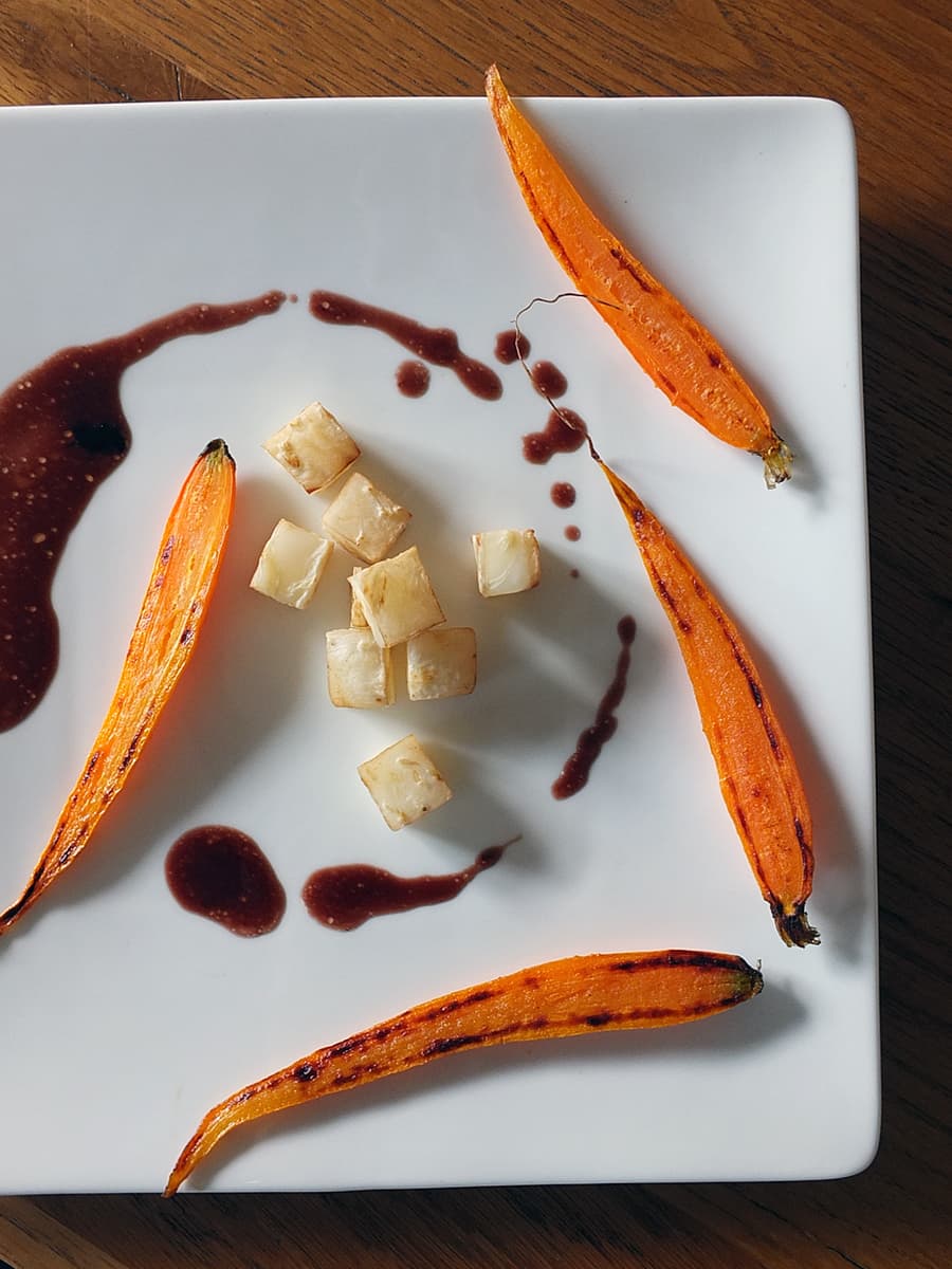 Image of Red wine jus on a plate with grilled vegetable garnishes.