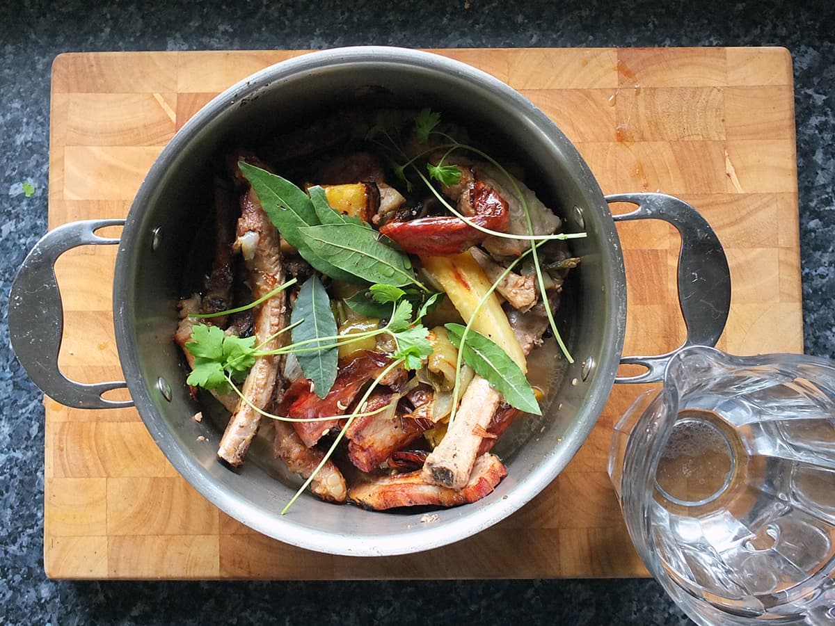 Photo of roasted pork bones and vegetables ready to be simmered in a stock pot.