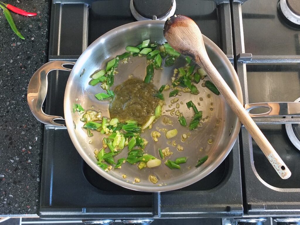 Top down image of curry cooking after Thai green curry paste added to the pan.
