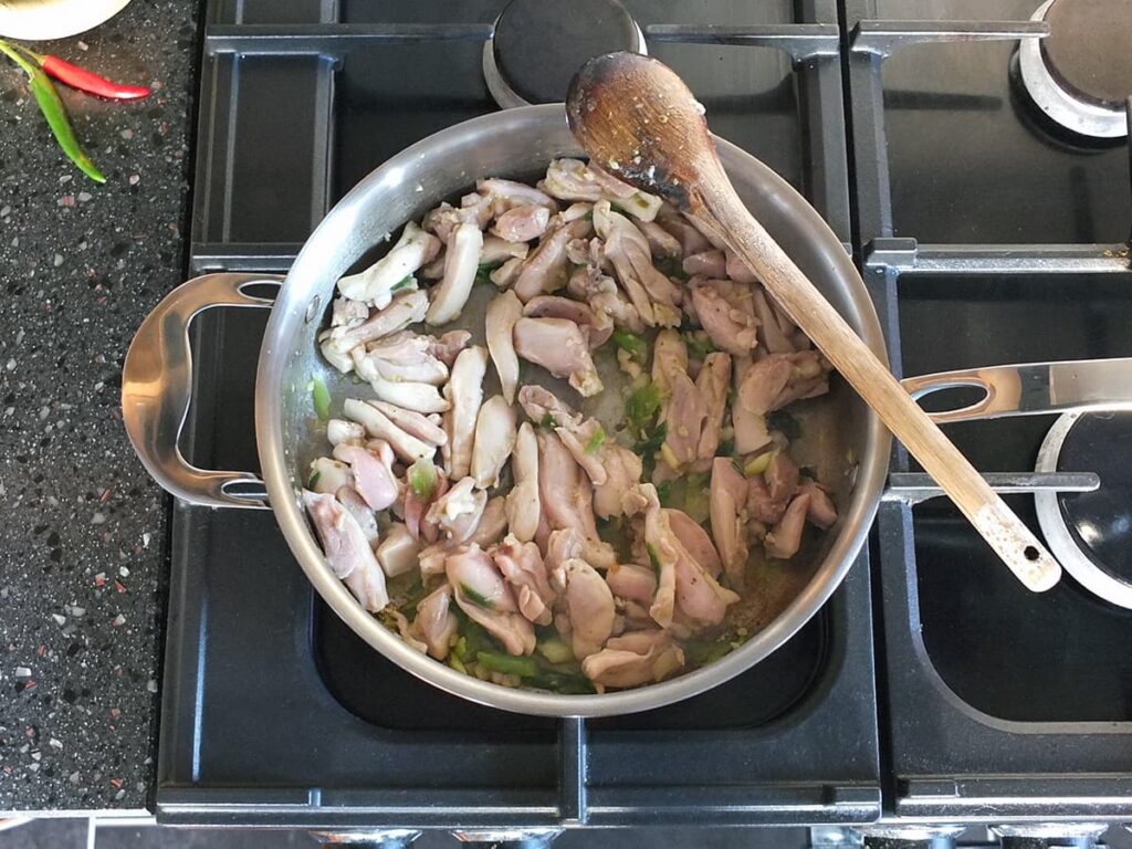 Image of chicken thigh strips browned in a saute pan.
