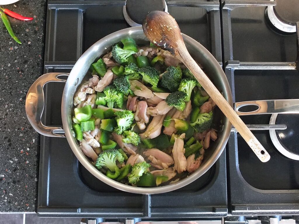Saute pan with broccoli and green pepper chunks in the mix.