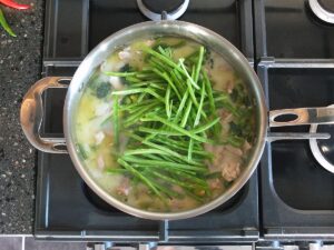 Image of lengthwise halved green beans showing off the vibrant inner seeds after they've been added to the pan.