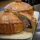 Image of two traditional British pork pies one with a slice cut out of it to show the meaty insides.