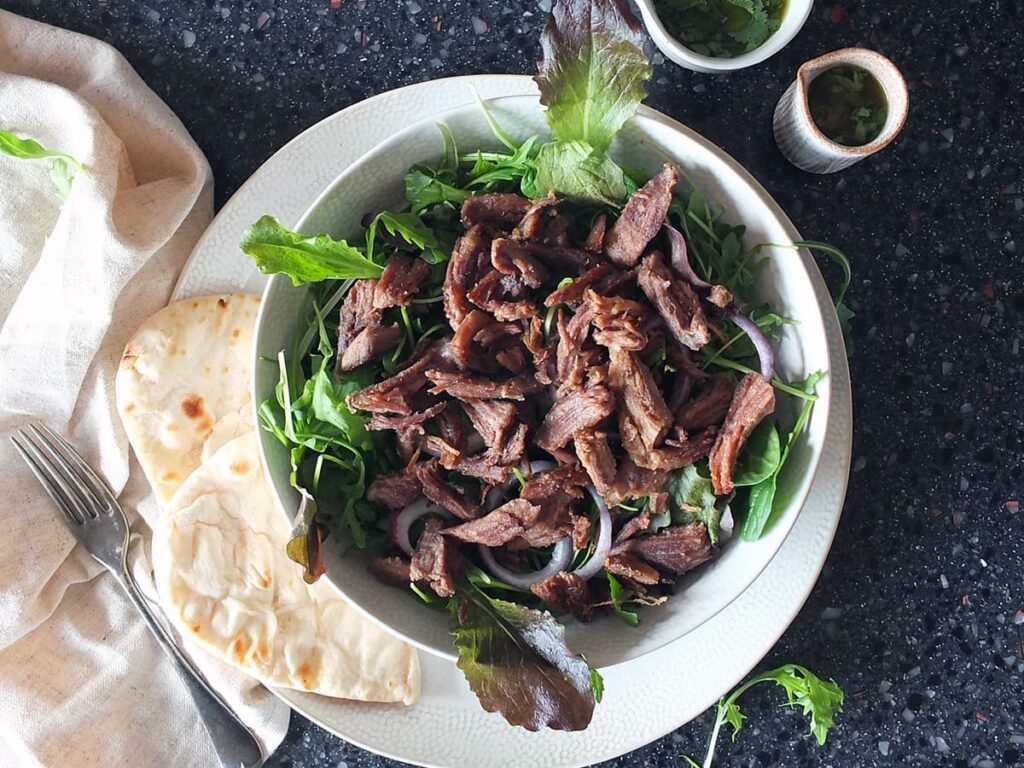 Image of crispy lamb on a bed of salad leaves.