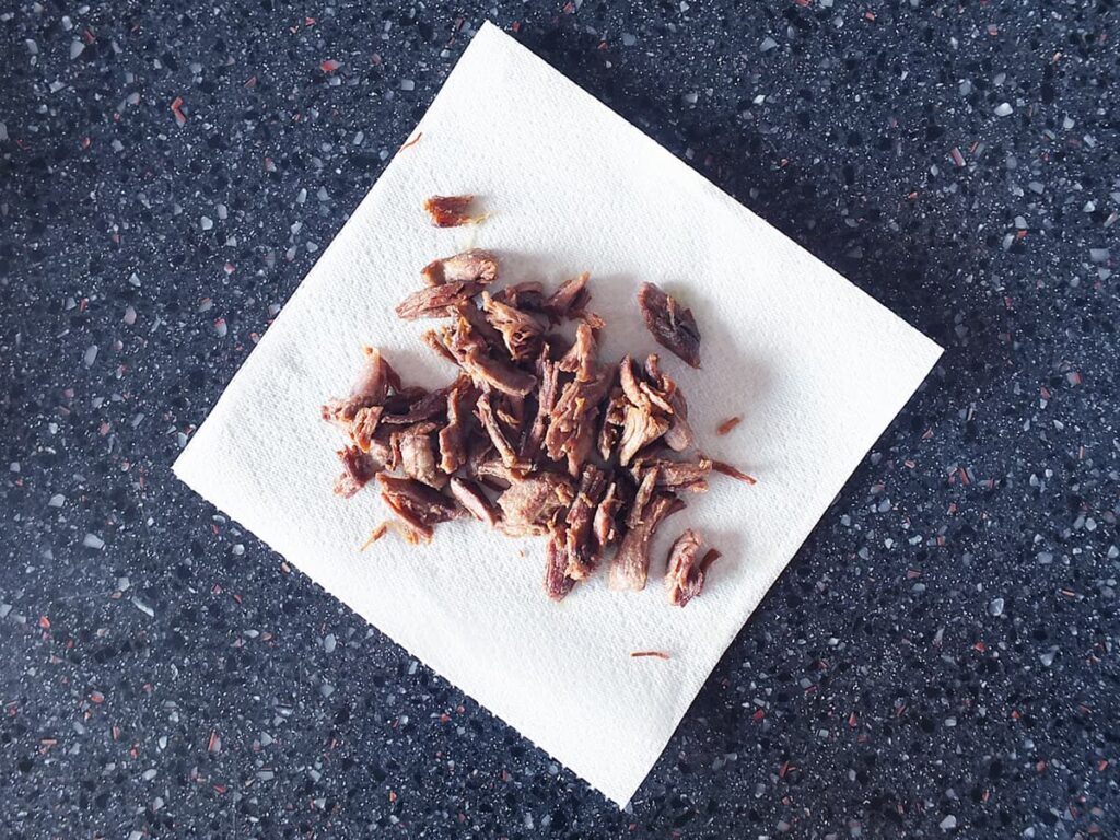 Image of crispy lamb draining on kitchen towel.