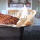 Close up image of banana bread in a loaf tin cooling on the countertop.