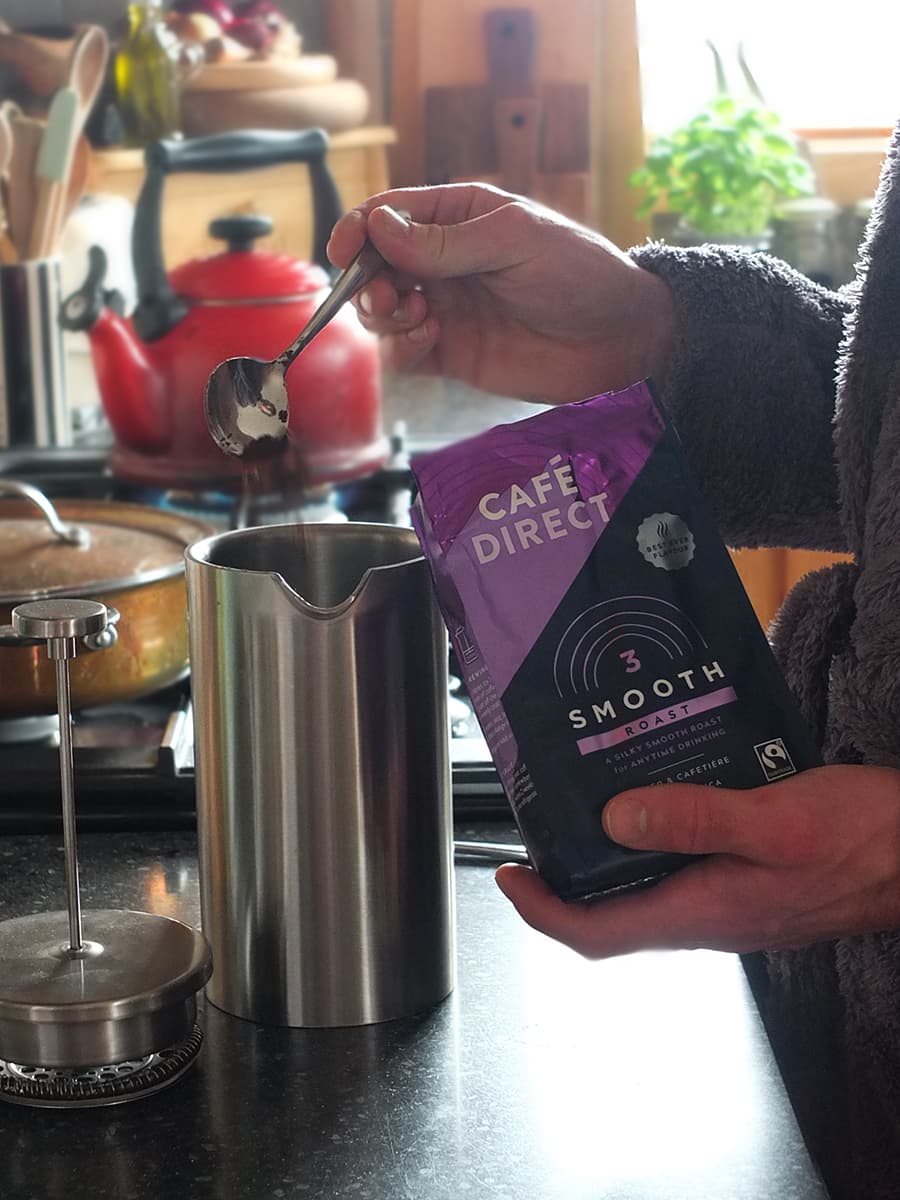 Image of man spooning coarse coffee into a cafetiere.