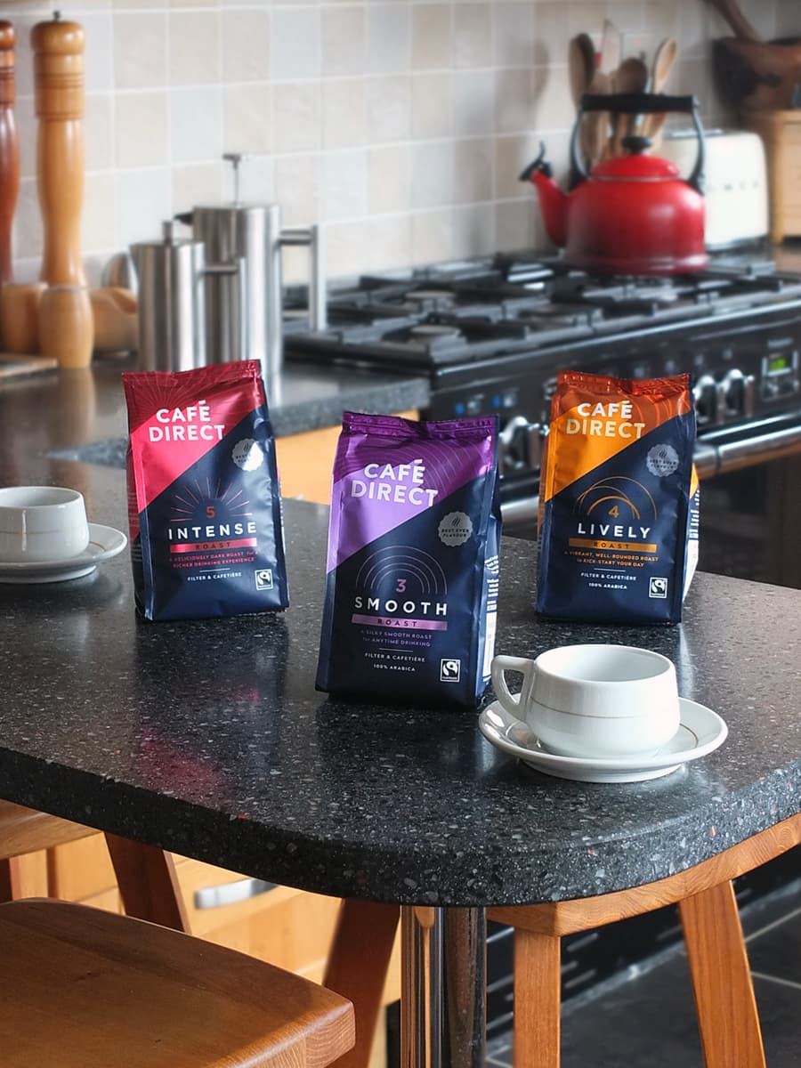 Image of three types of Cafedirect coffee on a breakfast bar with stools.