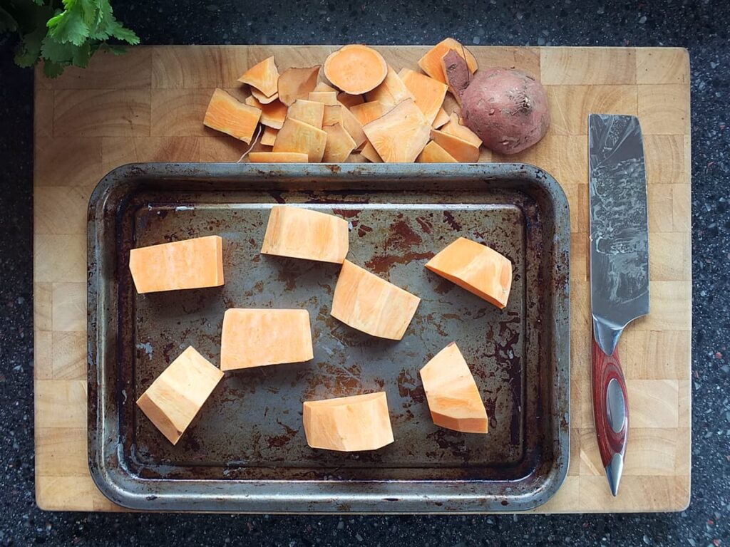Photo of peeled, cubed sweet potato on an old baking tray.