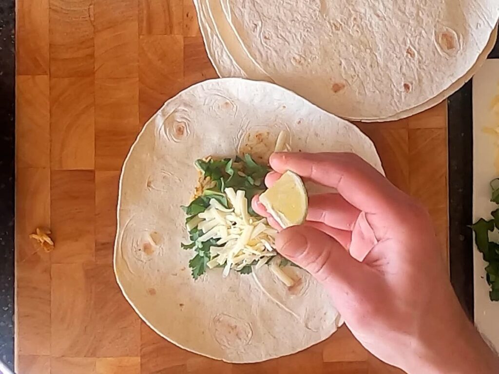 Image of man holding lime wedge above burrito.