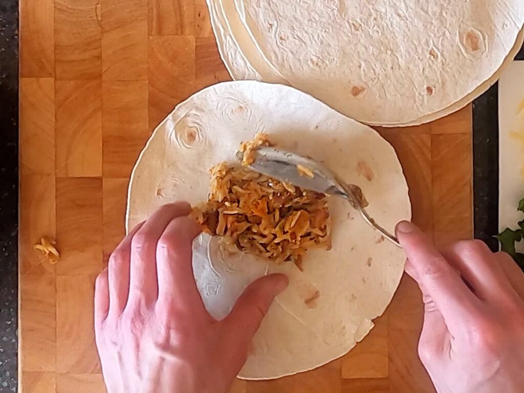 Image of pan spooning filling onto tortilla.