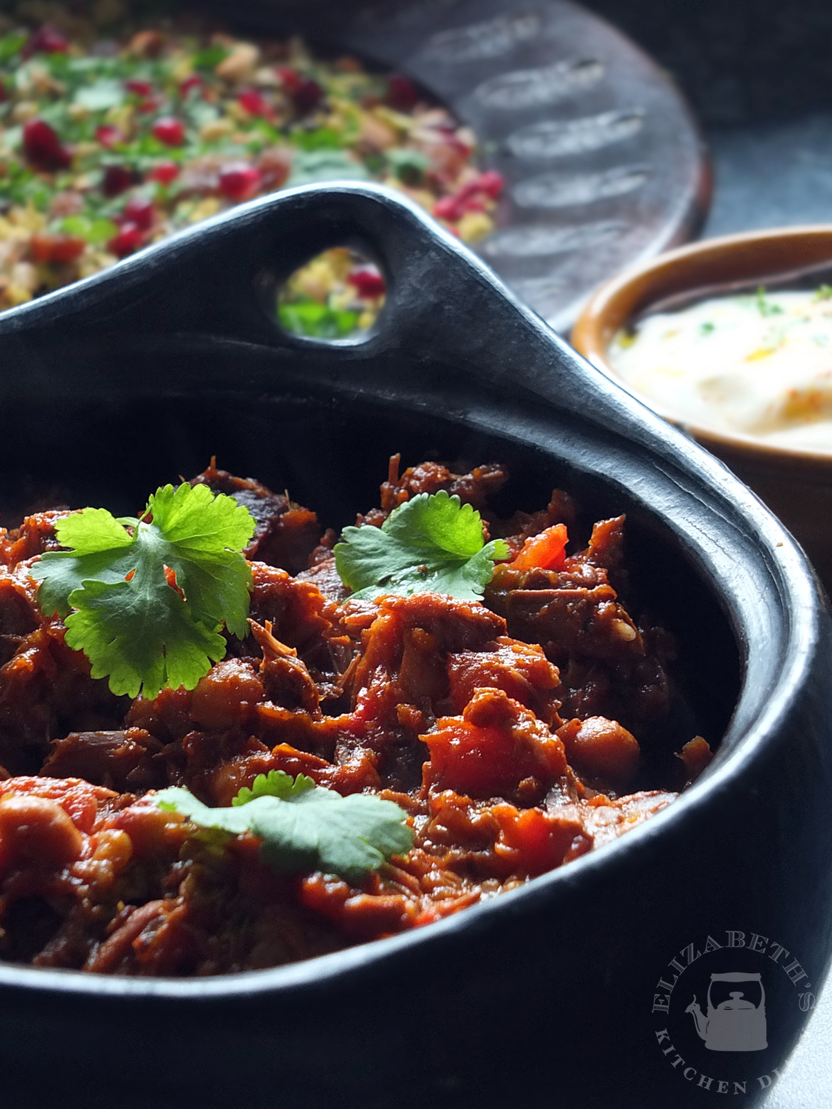 Close up image of slow cooked Moroccan lamb in a black pottery bowl.