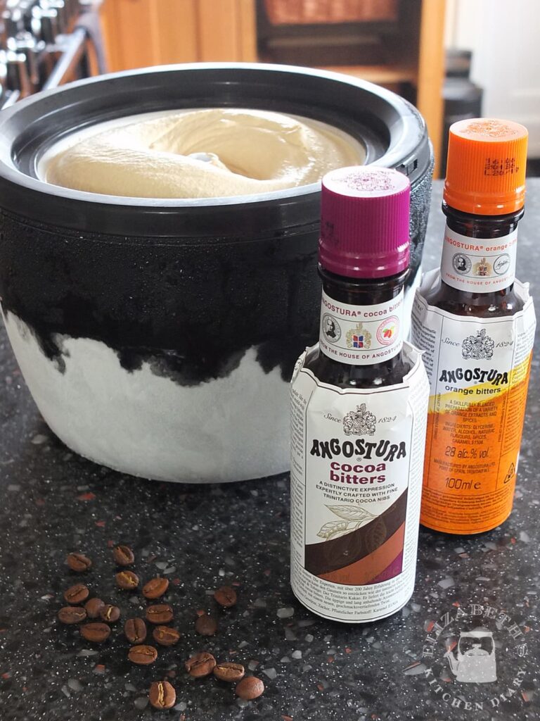 Image of a bottle of Angostura cocoa bitters and Angostura orange bitters beside an ice cream machine bowl with freshly churned coffee ice cream in it.