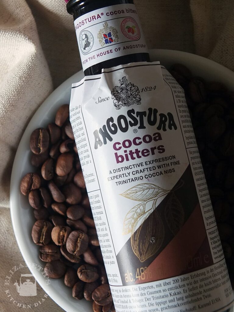 Close up image of the label of a bottle of Angostura cocoa bitters with coffee beans in the background.