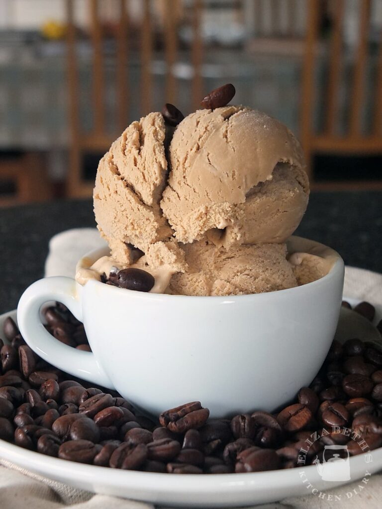 Small white espresso cup with two large scoops of coffee ice cream in it.
