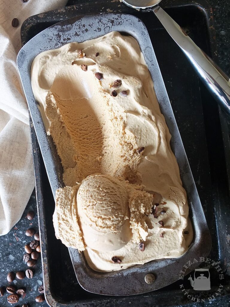 Image of a cast iron bread tin with coffee ice cream with one scoop half scooped out.