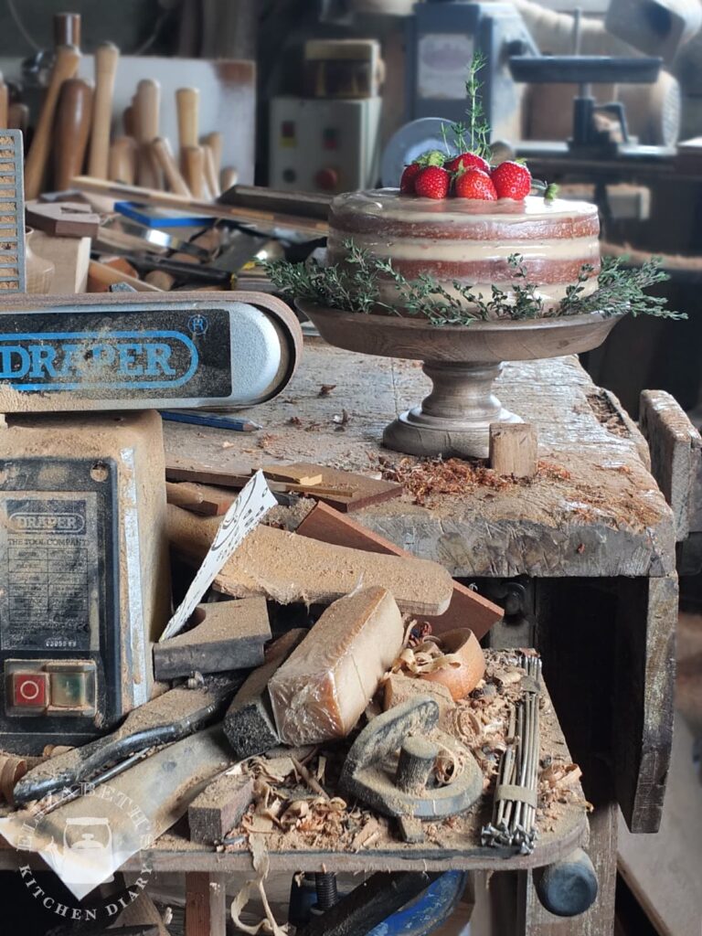 Image of a birthday cake for a 70 year old man in a wood turning workshop. There is sawdust everywhere!