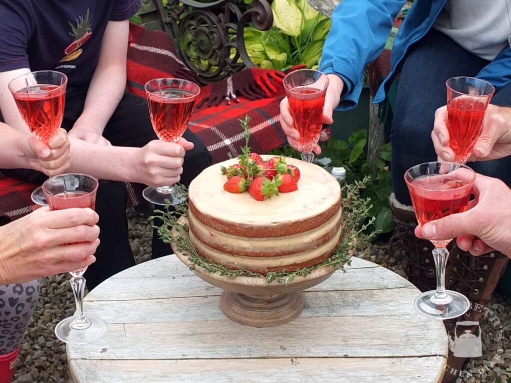 Photo of a family enjoying an outdoor garden birthday party, toasting the birthday boy with champagne flutes filled with non-alcoholic juice.