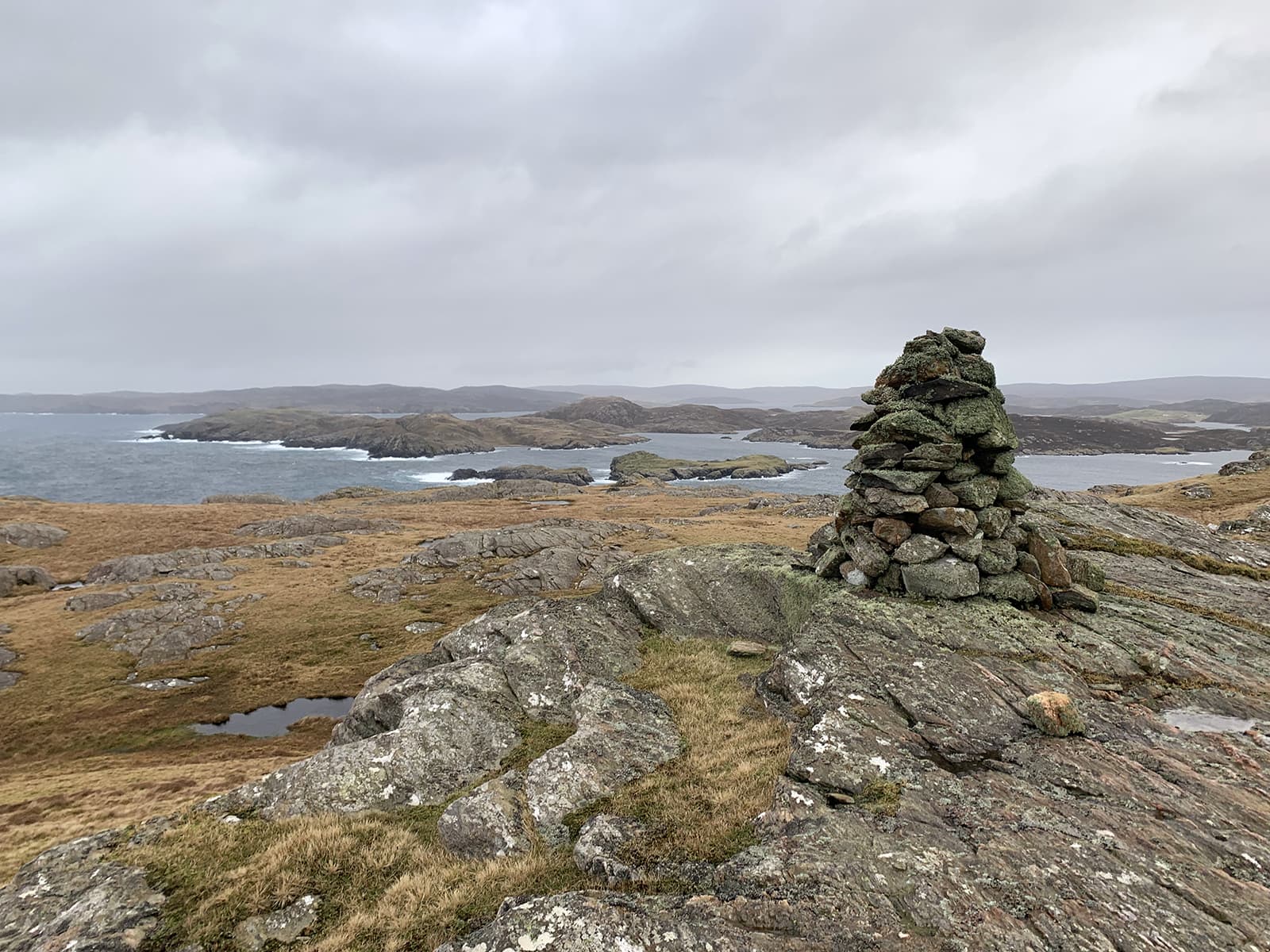 Image of a cairn at the top of Neeans Neap with the island of Vementry in the background.