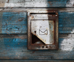Subscribe to Elizabeth's Kitchen Diary. Image of an old fashioned rusty letter box with a mail icon on it and a distressed wooden house background.
